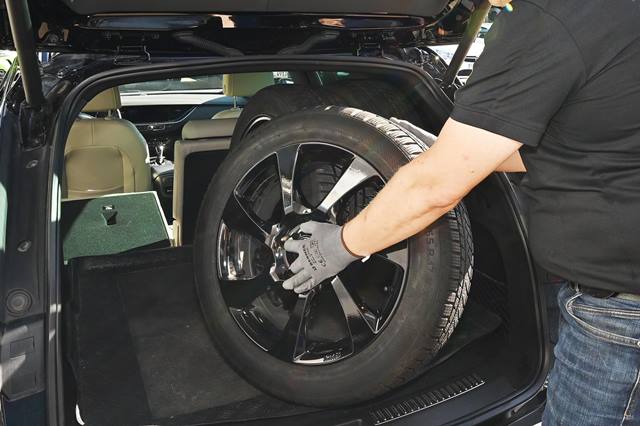Monteur verlädt Reifen im Kofferraum