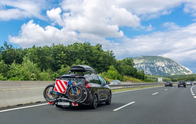 Auto mit Dachbox auf Autobahn Richtung Berge