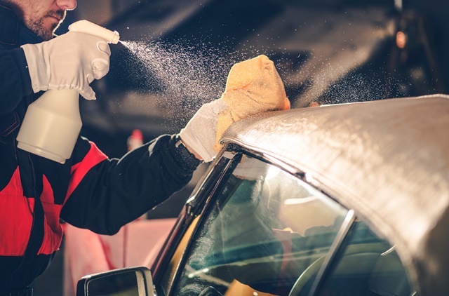 Kfz-Mechatroniker mit Imprägnierspray am Cabrio-Dach