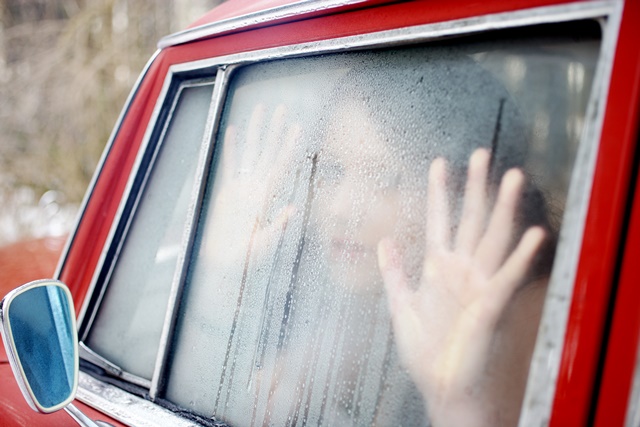 Frau guckt aus von innen feuchtem Autofenster