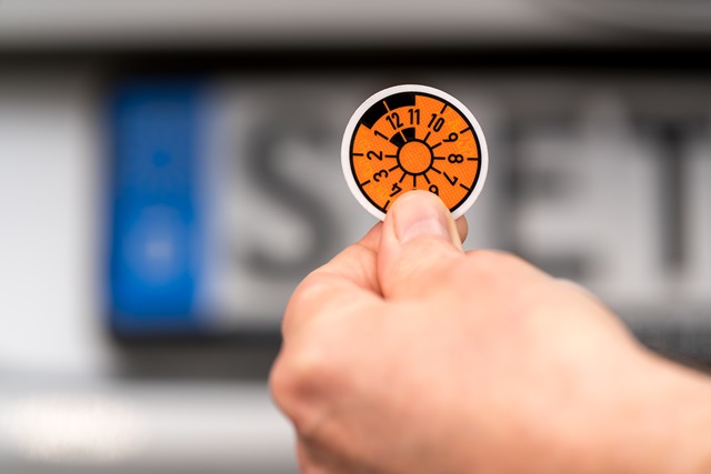 Nummernschild mit orangefarbener HU-Plakette