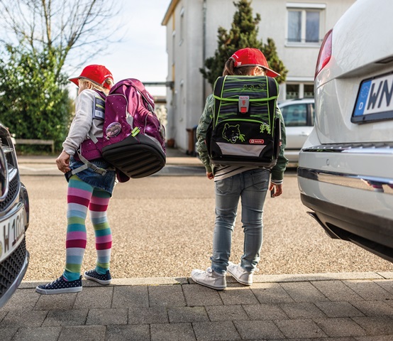 ABC-Schützen zwischen zwei Autos schauen auf die Straße