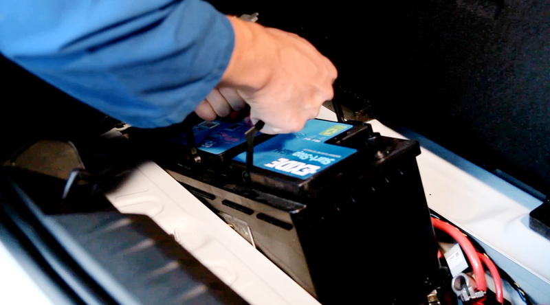 Kfz-Mechatroniker holt Auto-Batterie aus Auto heraus