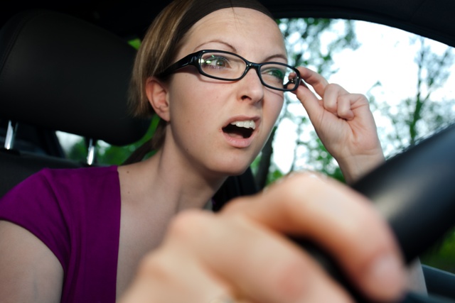 Frau am Steuer fässt sich an die Brille und sieht trotzdem schlecht