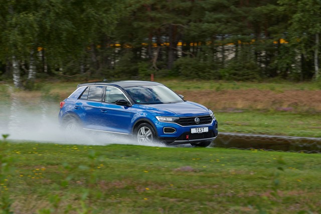 Blaues Auto fährt beim Sommerreifentest durch große Pfütze